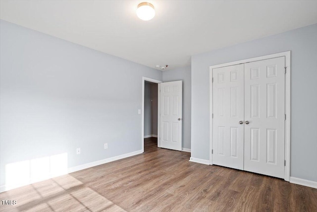 unfurnished bedroom with a closet, baseboards, and wood finished floors