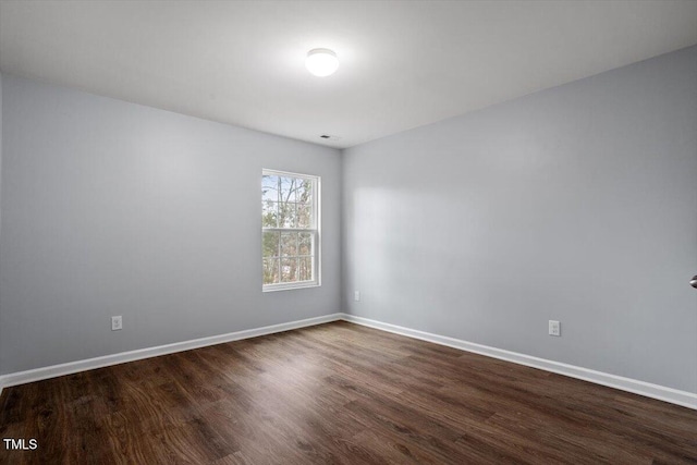 unfurnished room with dark wood-style floors and baseboards