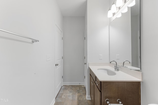 bathroom featuring stone finish floor, vanity, and baseboards