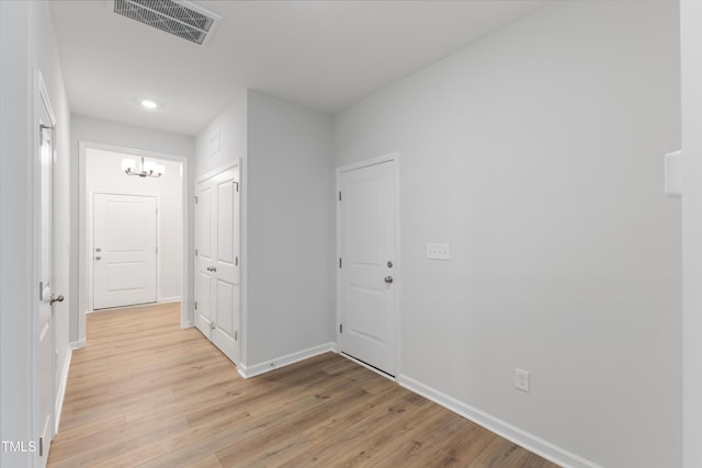 corridor featuring light wood-type flooring, visible vents, and baseboards