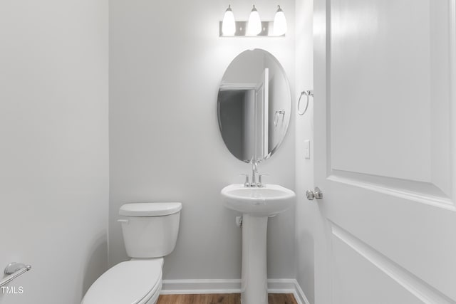 bathroom featuring baseboards, a sink, toilet, and wood finished floors