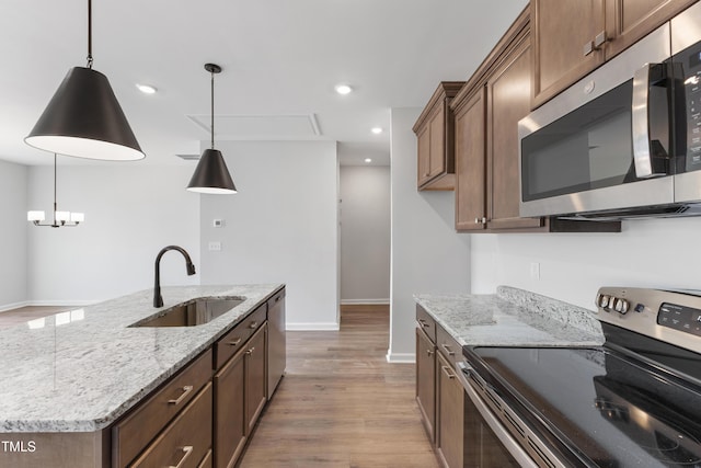 kitchen featuring stainless steel appliances, recessed lighting, hanging light fixtures, light wood-style flooring, and a sink