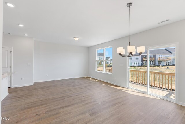 interior space featuring a wealth of natural light, visible vents, an inviting chandelier, and wood finished floors