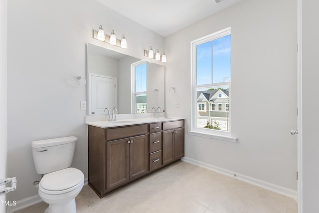 full bath featuring double vanity, baseboards, toilet, and a sink