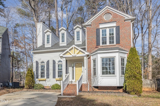 view of front of property with roof with shingles, central AC, and brick siding