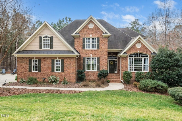 traditional home featuring brick siding, a standing seam roof, metal roof, and a front lawn