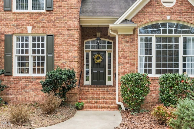 entrance to property with brick siding and roof with shingles