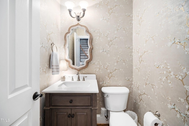 half bathroom with wallpapered walls, toilet, and vanity