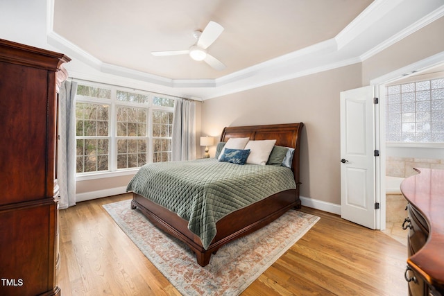 bedroom with a raised ceiling, baseboards, light wood finished floors, and ornamental molding