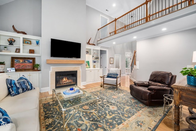 living area with stairway, a fireplace with flush hearth, wood finished floors, and a towering ceiling