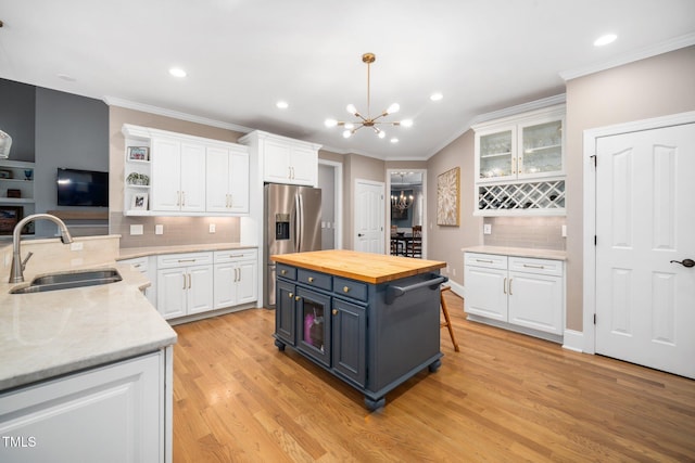 kitchen featuring white cabinetry, butcher block countertops, a chandelier, and a sink