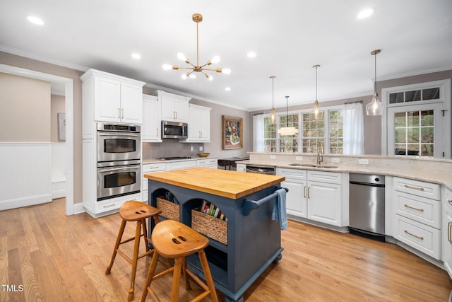 kitchen featuring wooden counters, appliances with stainless steel finishes, crown molding, and a sink