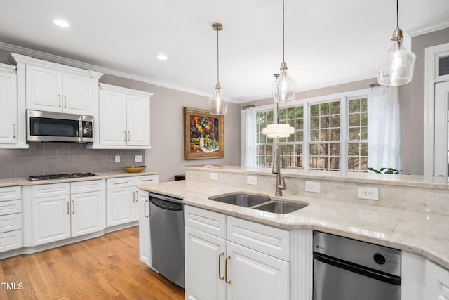 kitchen with tasteful backsplash, white cabinetry, light wood-style floors, appliances with stainless steel finishes, and crown molding