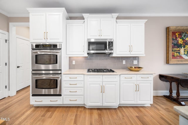 kitchen featuring crown molding, light wood-style floors, tasteful backsplash, and appliances with stainless steel finishes