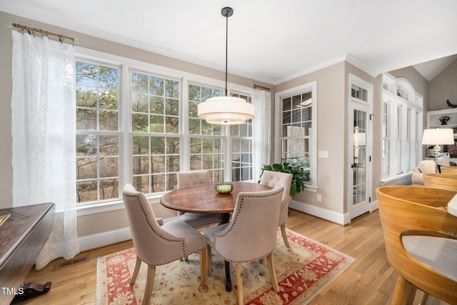 dining space with light wood-type flooring, baseboards, visible vents, and crown molding