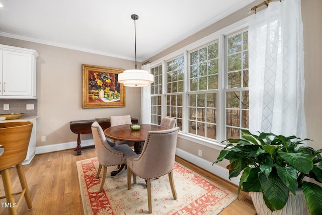 dining room with baseboards, light wood-style floors, and ornamental molding