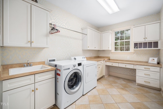 washroom with a sink, cabinet space, independent washer and dryer, and wallpapered walls