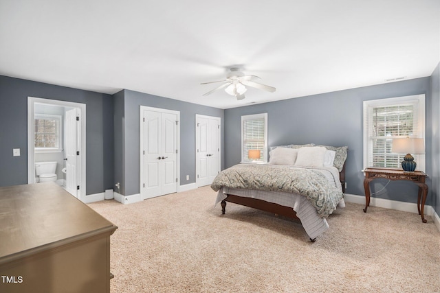 bedroom with baseboards, multiple closets, and light colored carpet