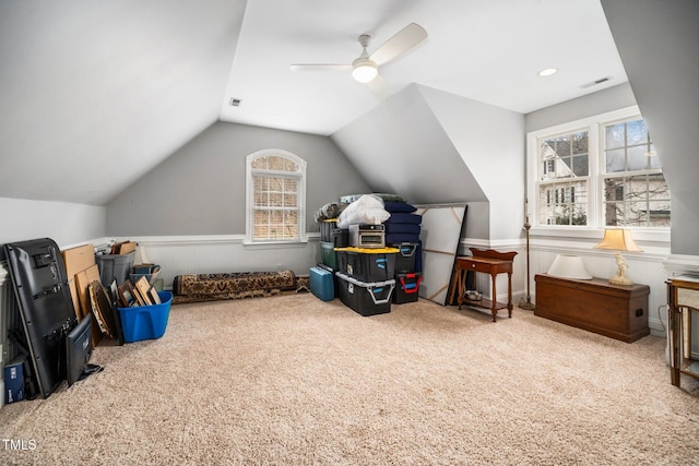 game room with a ceiling fan, a wainscoted wall, visible vents, carpet floors, and vaulted ceiling