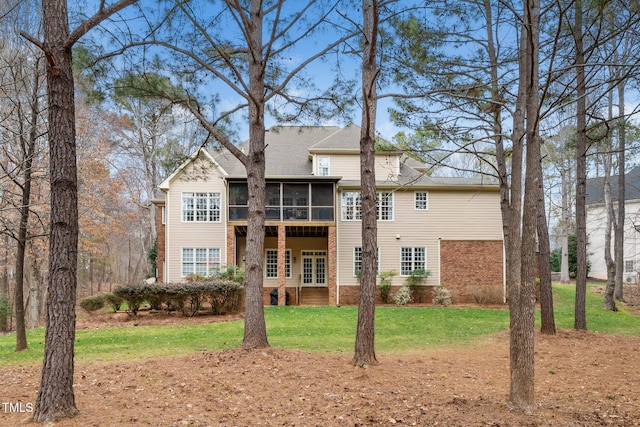 rear view of house featuring a lawn and a sunroom