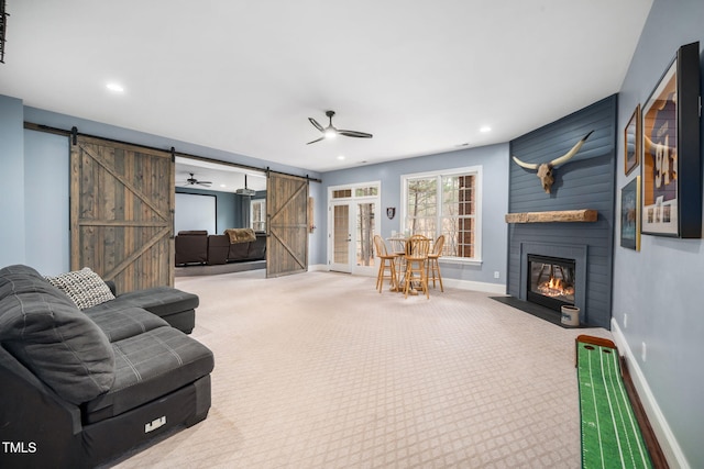 living room with recessed lighting, a barn door, a large fireplace, carpet, and baseboards