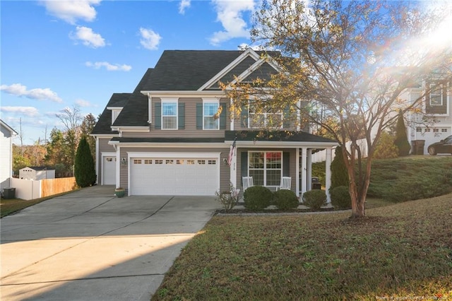 view of front of home featuring a porch, a garage, fence, driveway, and a front lawn