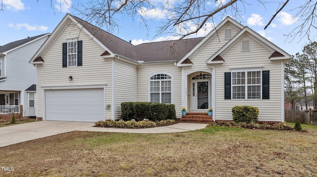 traditional-style home with roof with shingles, concrete driveway, a front yard, fence, and a garage