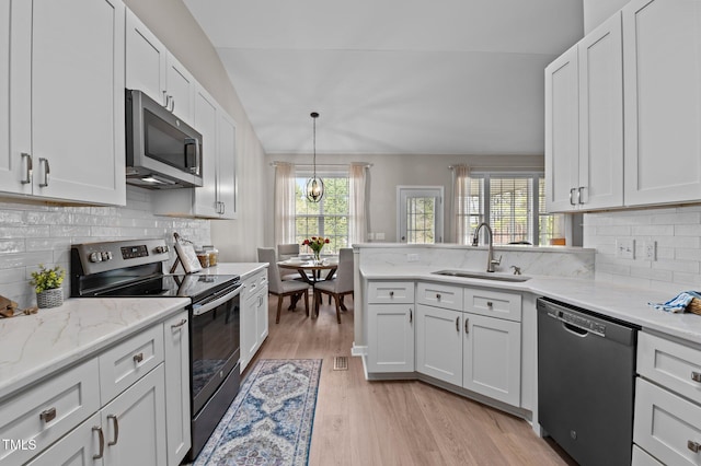 kitchen featuring appliances with stainless steel finishes, lofted ceiling, a sink, and plenty of natural light