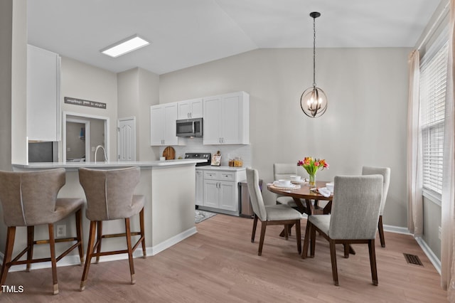 kitchen with visible vents, stainless steel microwave, a kitchen bar, white cabinetry, and a notable chandelier