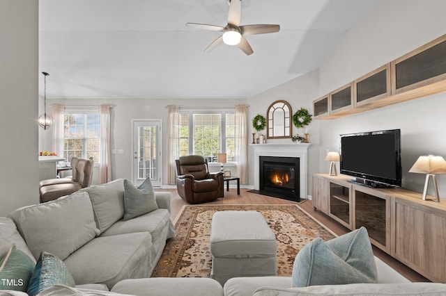 living room featuring a fireplace with flush hearth, wood finished floors, plenty of natural light, and ceiling fan