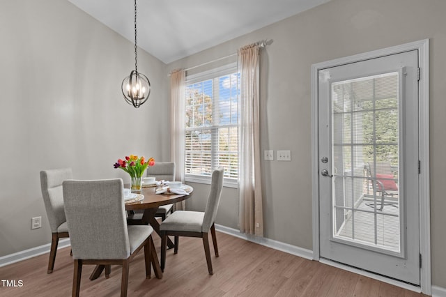 dining room with light wood finished floors, baseboards, vaulted ceiling, and a chandelier