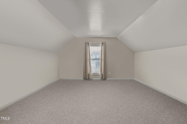 additional living space featuring vaulted ceiling, carpet flooring, visible vents, and baseboards