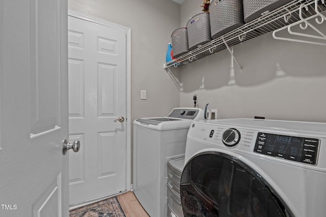 washroom featuring laundry area, separate washer and dryer, and light wood-type flooring