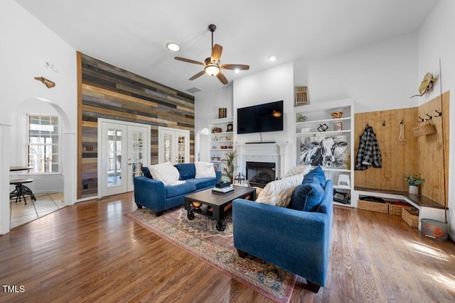 living area with arched walkways, a fireplace, wood finished floors, and wooden walls