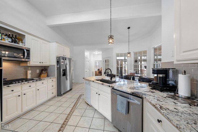 kitchen with appliances with stainless steel finishes, light tile patterned flooring, a sink, and lofted ceiling with beams