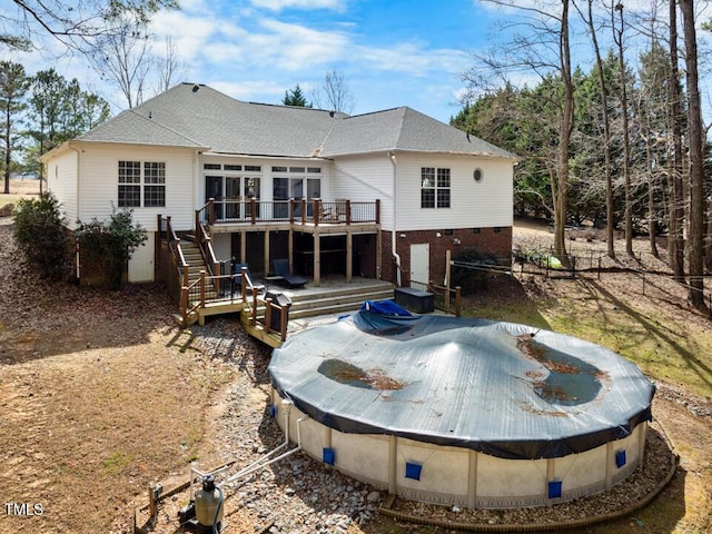 back of property with roof with shingles, stairway, and a wooden deck