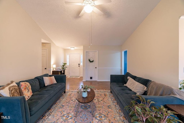 living room with lofted ceiling, a textured ceiling, and wood finished floors