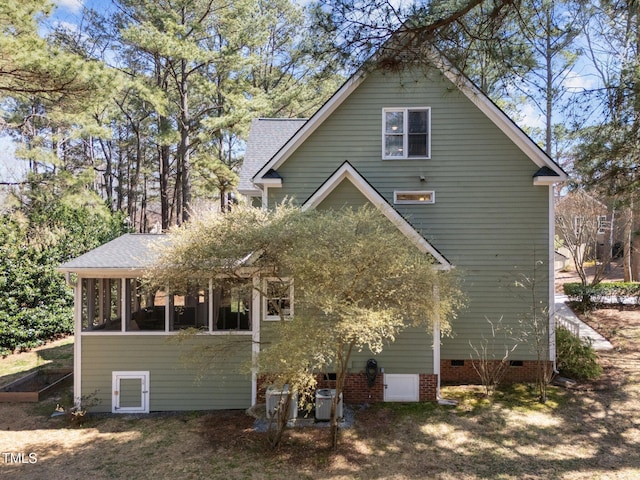 rear view of property featuring a shingled roof, a sunroom, and crawl space