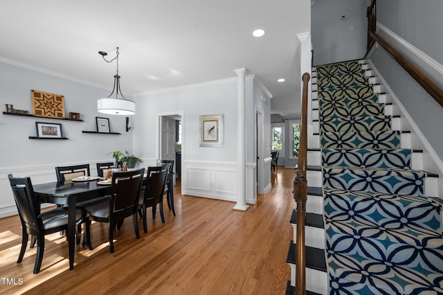 dining room with a wainscoted wall, light wood-style flooring, recessed lighting, stairs, and crown molding