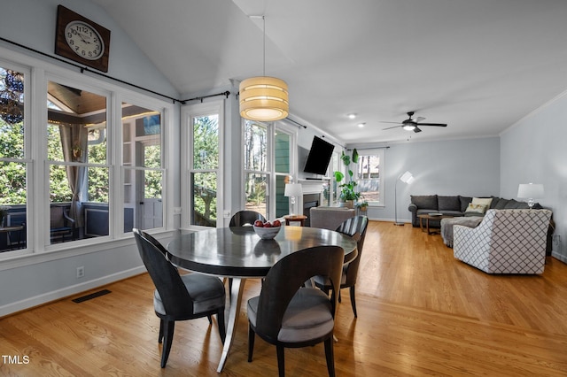 dining room featuring visible vents, baseboards, a fireplace, light wood-style floors, and crown molding