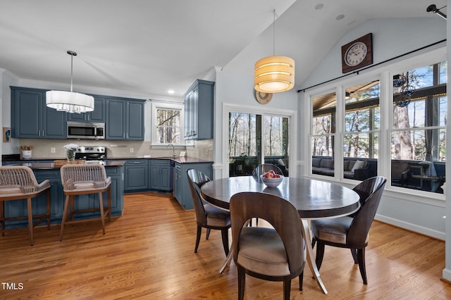 dining space featuring baseboards, lofted ceiling, and light wood finished floors