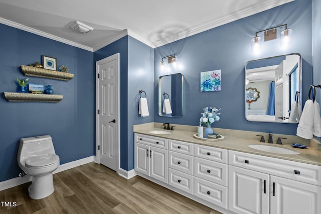 bathroom with toilet, ornamental molding, wood finished floors, and a sink