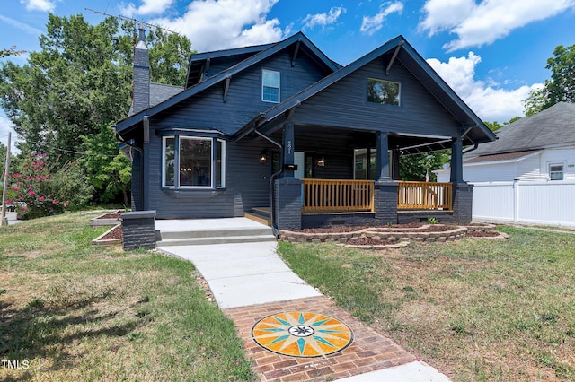 view of front of home featuring a front yard, covered porch, fence, and a chimney