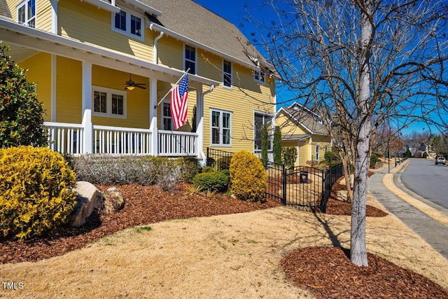 exterior space with covered porch, ceiling fan, a shingled roof, and a residential view