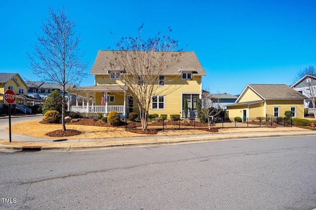 view of front of home with covered porch, a fenced front yard, and a residential view