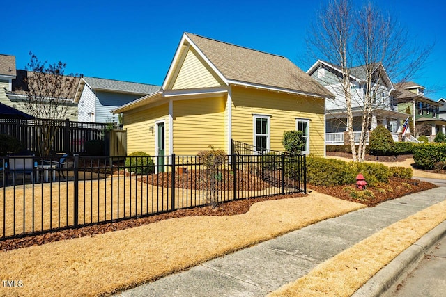 view of property exterior featuring roof with shingles and fence