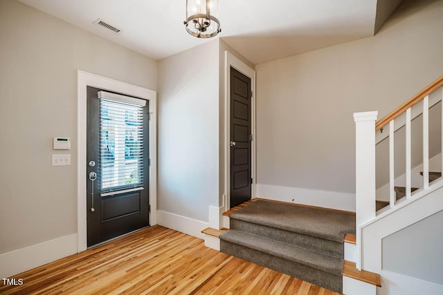 foyer with stairway, baseboards, visible vents, and wood finished floors