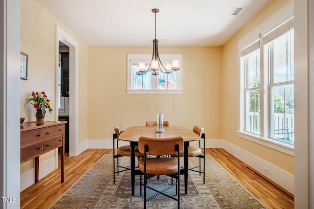 dining room featuring baseboards, visible vents, a chandelier, and wood finished floors