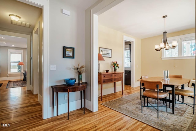 dining space featuring a chandelier, light wood-style flooring, and baseboards