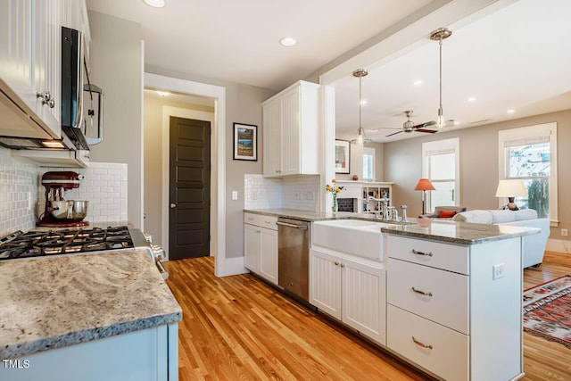 kitchen with a peninsula, a healthy amount of sunlight, a sink, and stainless steel dishwasher